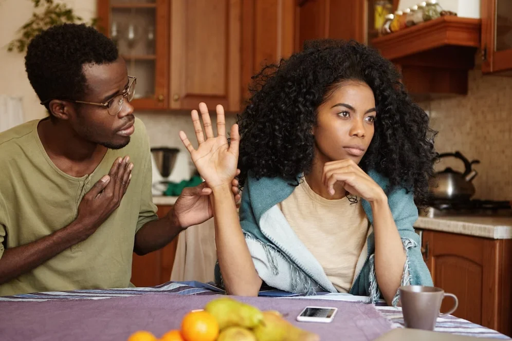 regretful-unhappy-young-african-american-male-glasses-trying-hard-sweet-talk-his-mad-offended-wife-who-is-sitting-him-kitchen-table-refusing-all-his-lies-people-relationships_273609-634